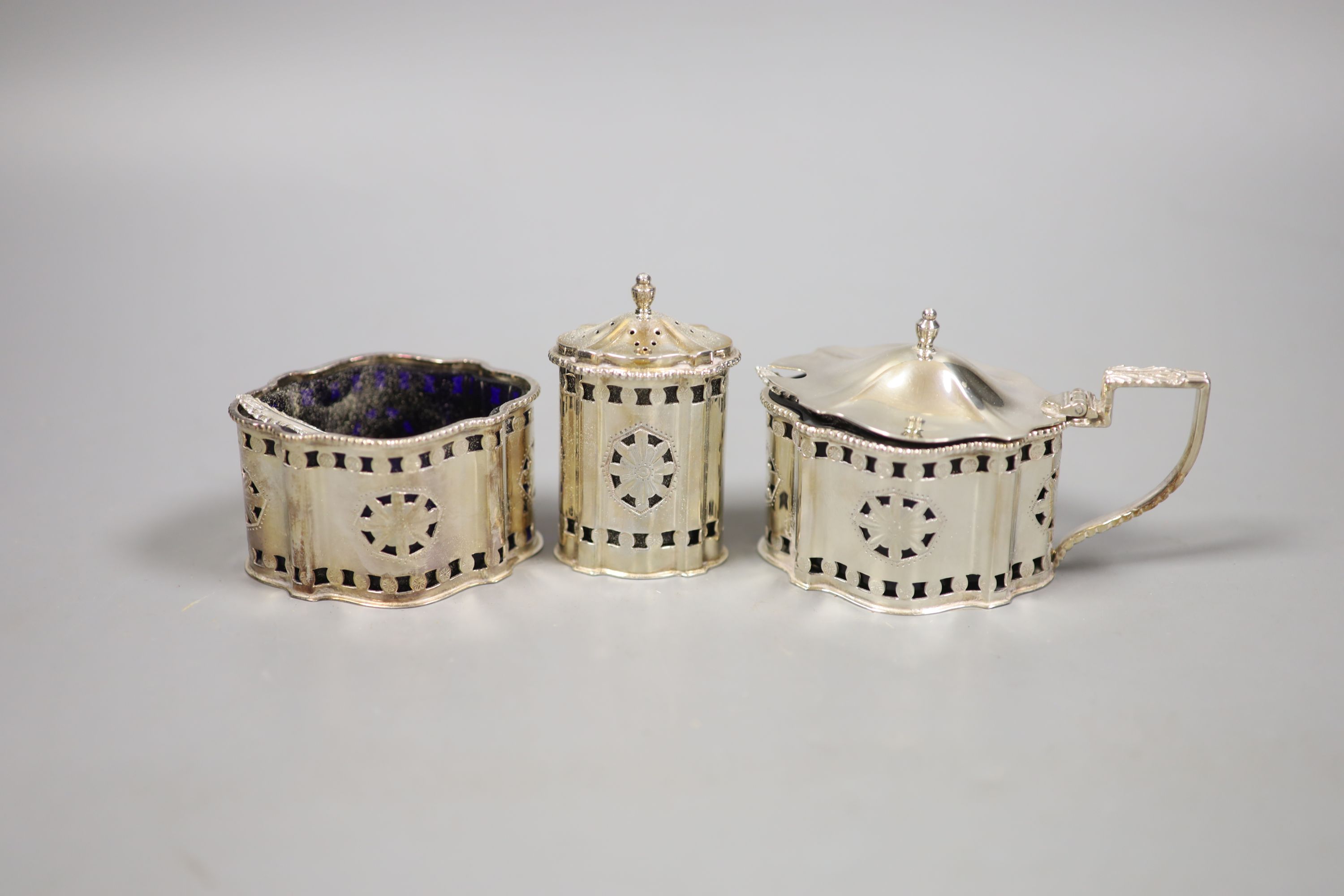 A modern George III style pierced and engraved shaped overal three peice condiment set